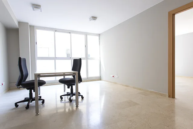 Despacho luminoso con mesa de trabajo para dos personas junto al ventanal