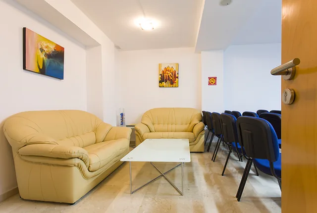 Sala de reuniones con sofás, mesa de centro y filas de sillas